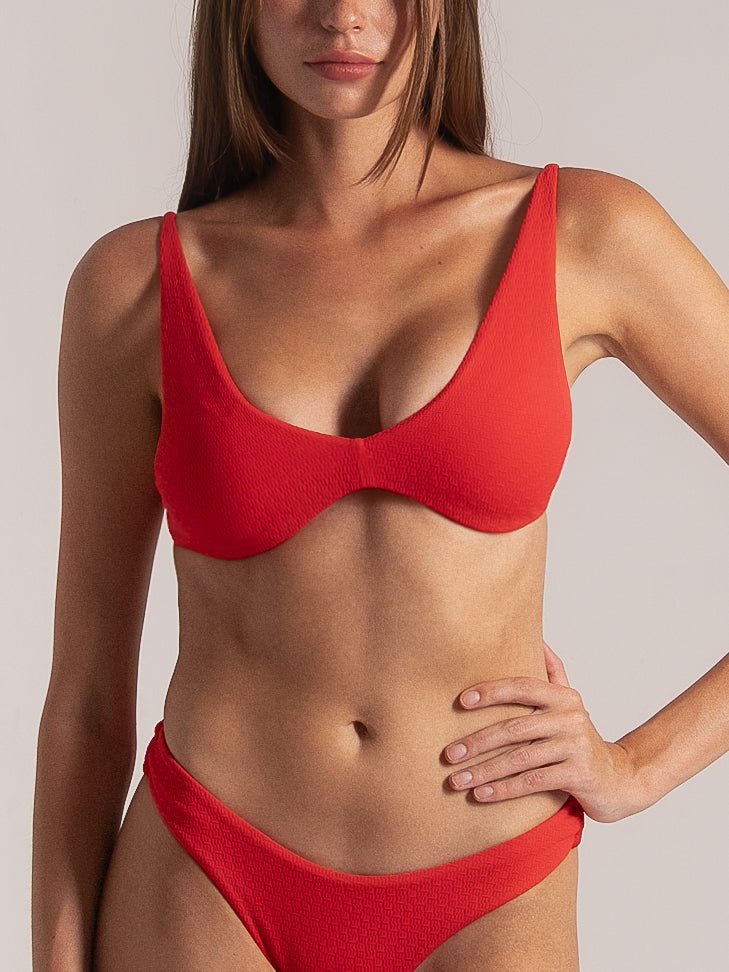 Front view of a red textured bikini set featuring a deep V underwire top and matching high-leg bottoms, modeled in a studio setting.
