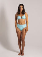 Woman wearing a shimmer aqua high-waisted bikini set with a ring detail at the center front of the top