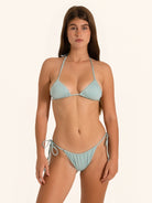 Front view of woman wearing light blue shimmer triangle bikini set with tie side bottom.