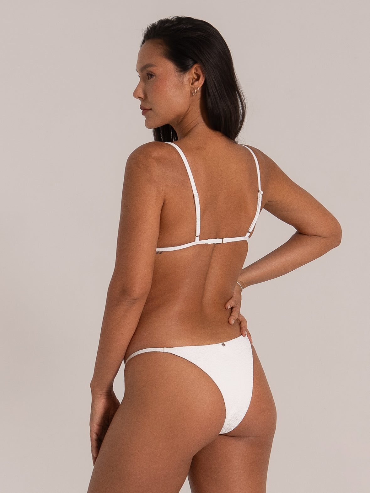 Side-back angle of textured white bikini top with adjustable straps