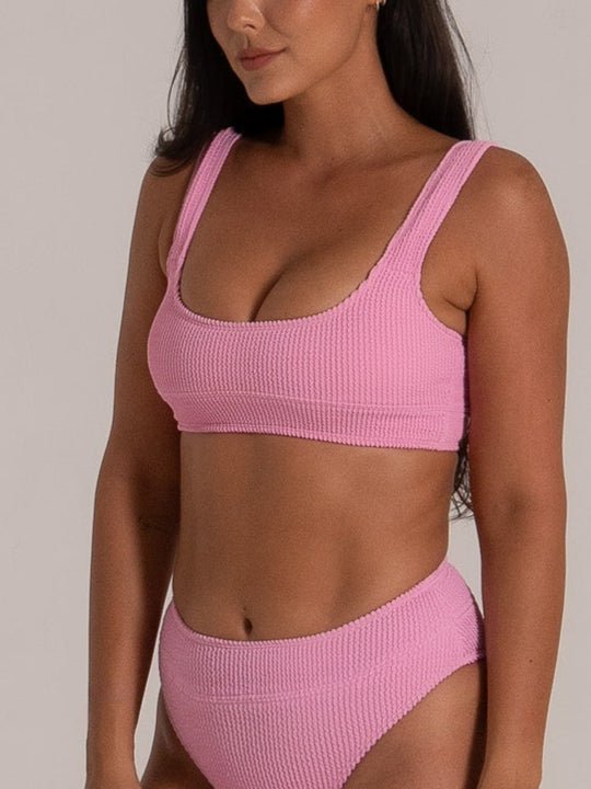 Model posing in pink textured square neck bikini top and high waisted bottom, side angle