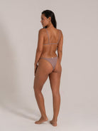 Woman turning slightly to the side wearing taupe textured bikini set with triangle top