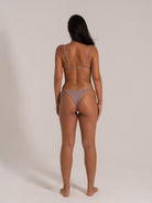 Rear view of woman in taupe triangle bikini set with thin adjustable straps and textured fabric