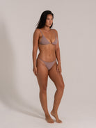 Woman modeling taupe textured triangle bikini with thin straps and subtle side tie