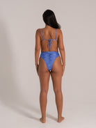 Woman wearing a textured blue high-waisted bikini, back view.