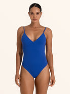 Front view of woman wearing blue textured V neck one piece swimsuit with adjustable straps.