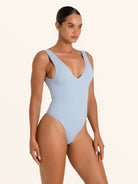 Side view of baby blue textured one piece swimsuit with V neck and wide straps.