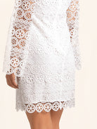 Side profile of white lace dress with blue trim neckline and bell sleeves