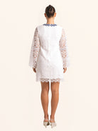 Back view of white lace mini dress with floral lace design and blue neckline trim