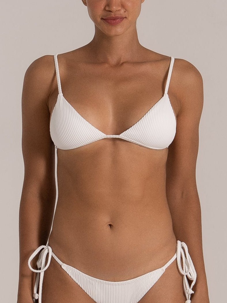 Close-up of model wearing white ribbed triangle bikini top and tie-side bottoms with fine textured fabric.