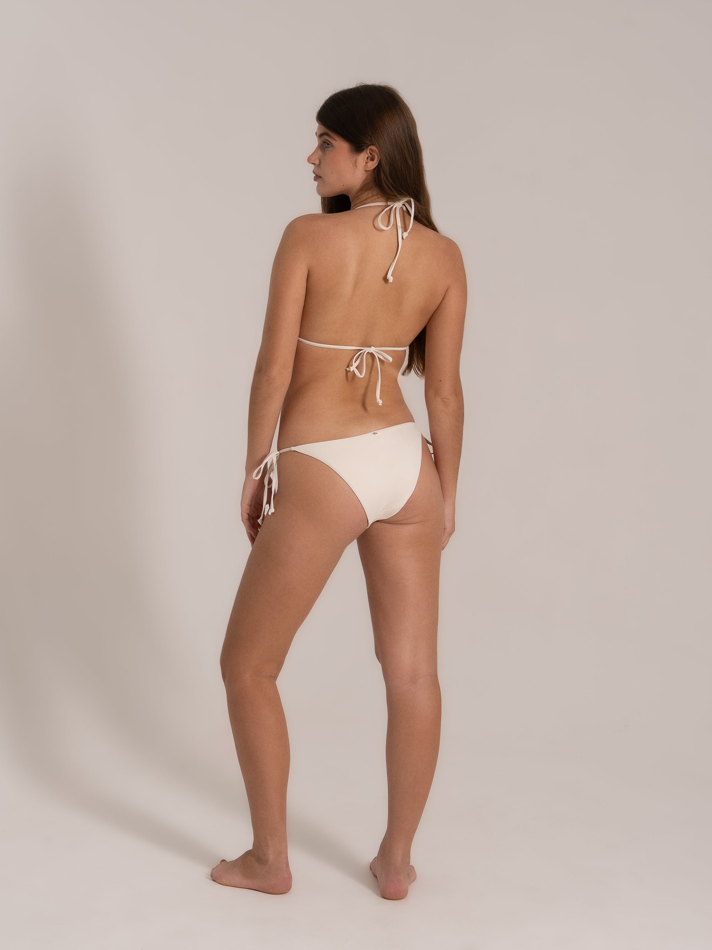 Model in white triangle bikini, angled from the back