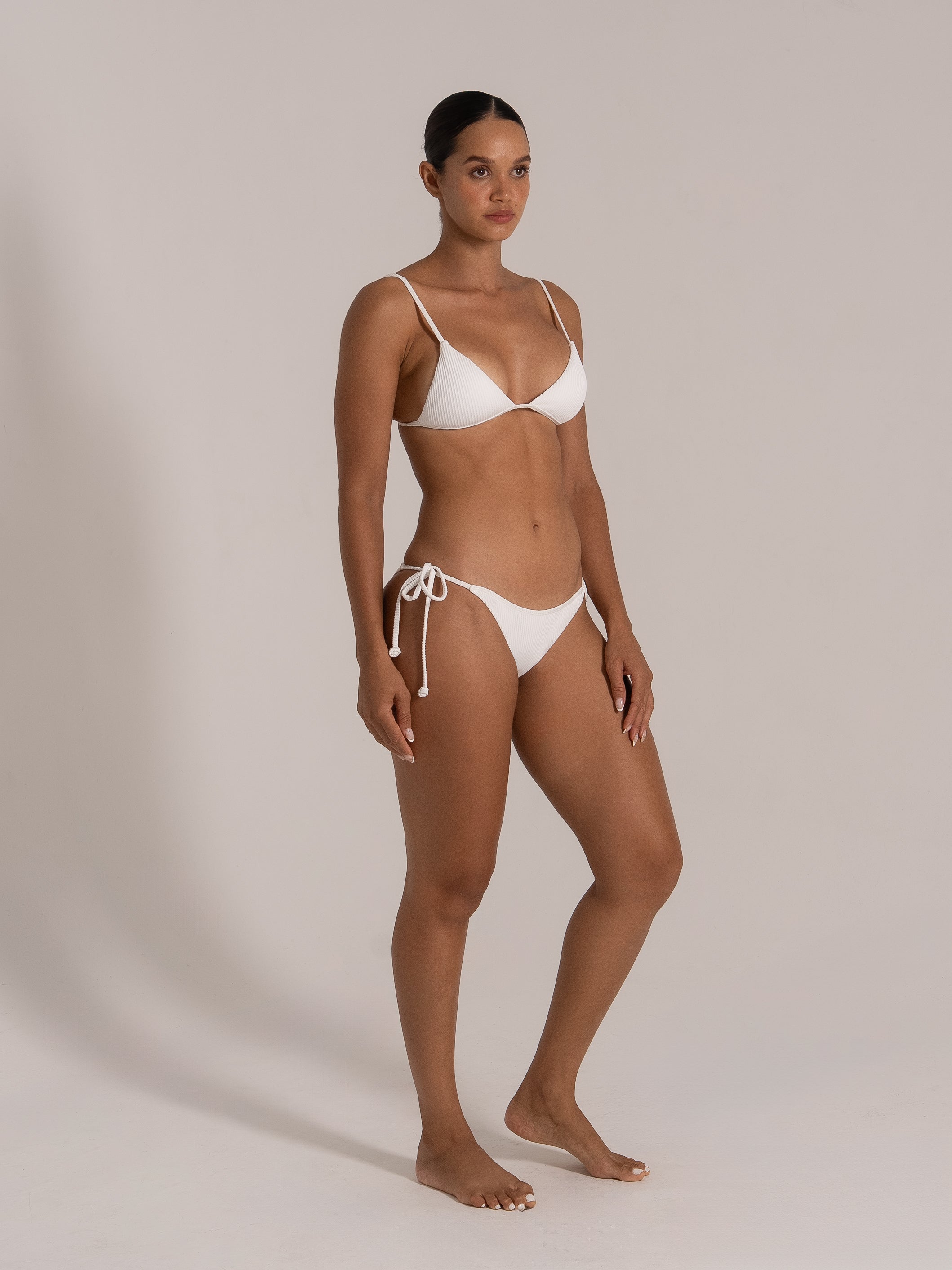 Side front angle of white triangle bikini set with ribbed texture and tie sides