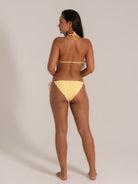 Model wearing yellow bikini with ring detail, back view