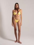 Model posing front-facing in yellow textured bikini with halter top and adjustable string bottoms.