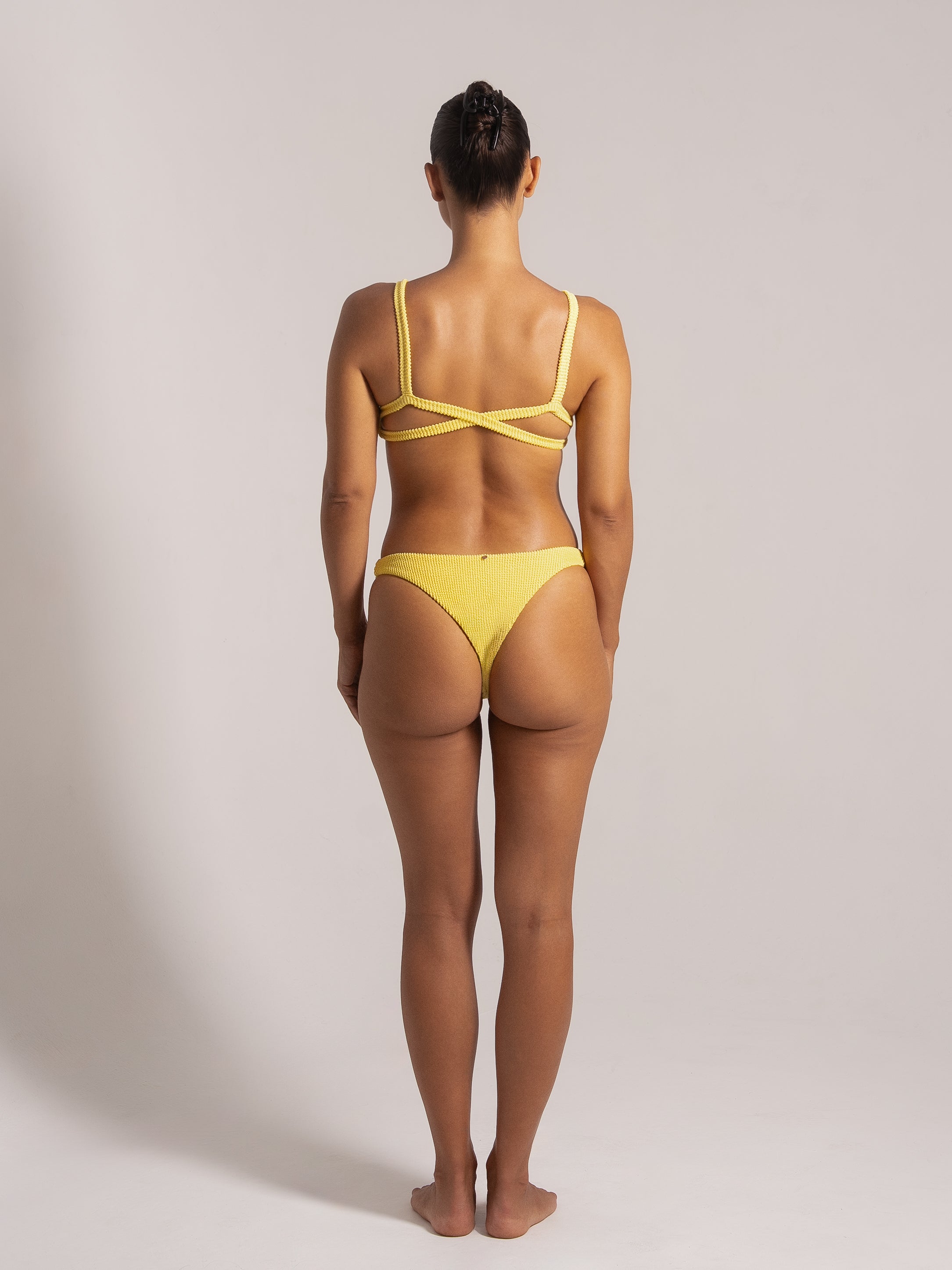 Back view of yellow textured bikini with cross-back strap detailing.