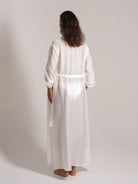 Ocean Mystery's floor-length white linen kimono dress with waist belt, featuring textured fabric and loose sleeves for minimalist loungewear.