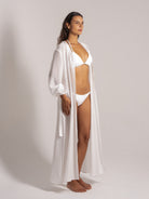 Ocean Mystery's sheer white robe over textured bikini set, showcasing minimalist beachwear against neutral backdrop for effortless summer styling.