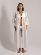 Ocean Mystery’s snow-white bikini set with oversized lantern-sleeve cardigan in a minimalist studio. Monochromatic coastal loungewear for effortless beach-to-resort styling.