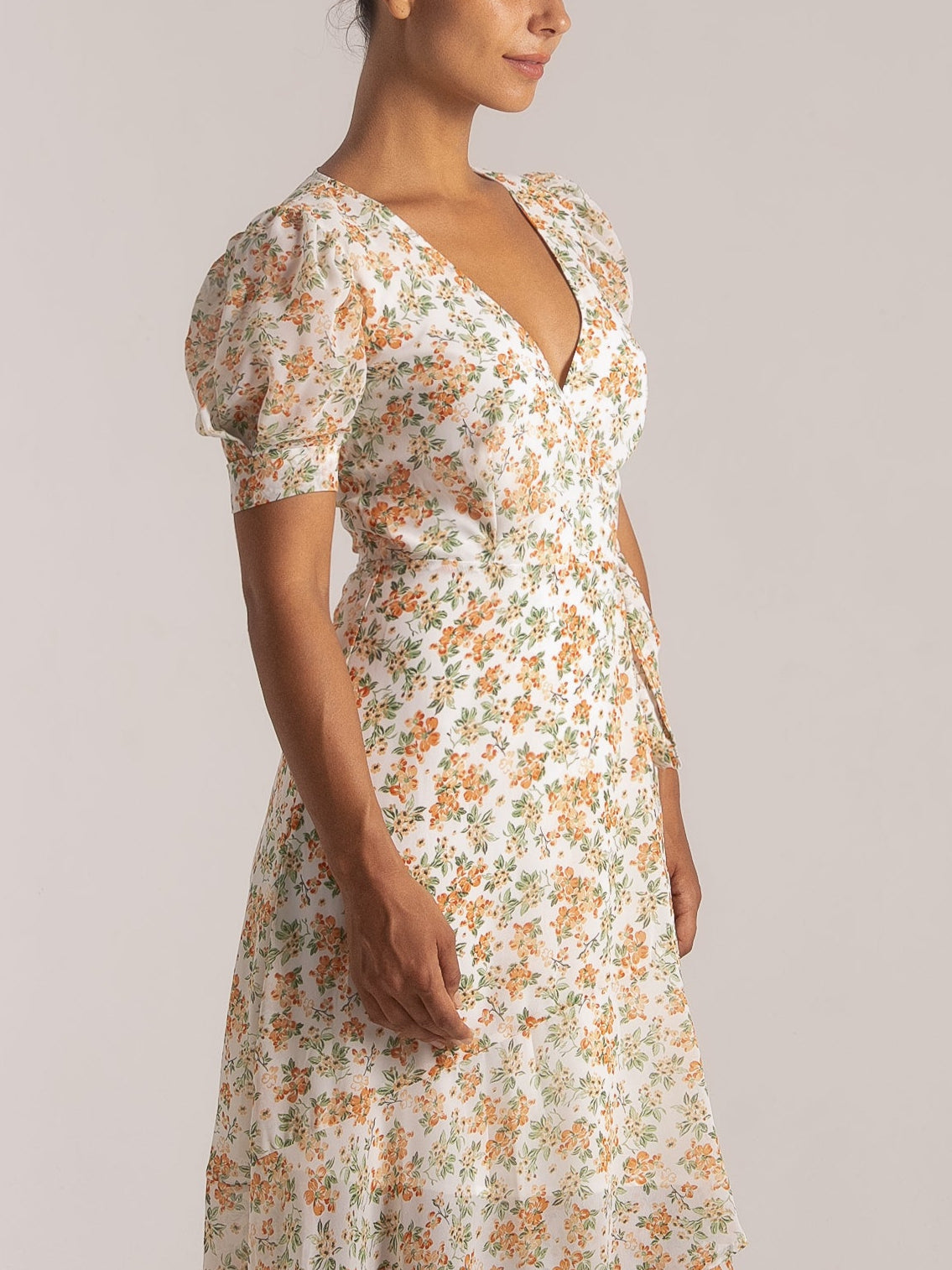 Ocean Mystery white floral V-neck dress with puff sleeves and asymmetrical hem featuring orange/green blooms.