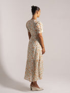 Ocean Mystery white floral midi dress with puff sleeves and orange/green blooms - back view with wedge heels.