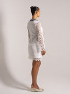 Ocean Mystery white lace mini dress with blue floral neckline and sheer long sleeves - back view for wedding guest outfits.
