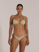Front-facing view of a woman in a light green triangle bikini with adjustable straps and textured fabric.