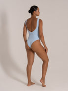 Side-back view of a baby blue textured one-piece swimsuit with deep scoop back design.