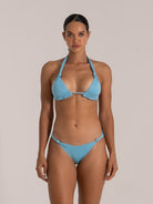 Front view of a woman wearing a sparkly baby blue halter bikini set with knotted details on the top and bottoms.