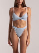 Front view of woman in baby blue textured bikini set with braided straps and high-waisted bottom