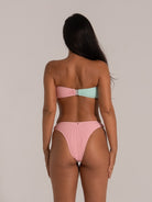 Woman wearing a backless two-tone bandeau bikini set in pink and mint green textured fabric, secured with a clasp back.