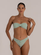 Model wearing bandeau bikini top in mint green with center knot twist
