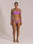 Front view of model in purple bandeau bikini set with tie sides