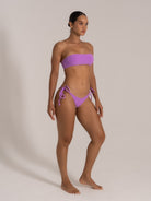 Side front view of purple bandeau bikini set on model