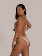 Back view of woman wearing a beige triangle bikini set with tie sides and halter neck design