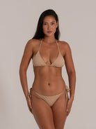Front view of model in beige halter triangle bikini set with tie sides, perfect for a minimal beach style