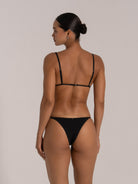 Woman wearing a black triangle bikini set with adjustable straps, back view