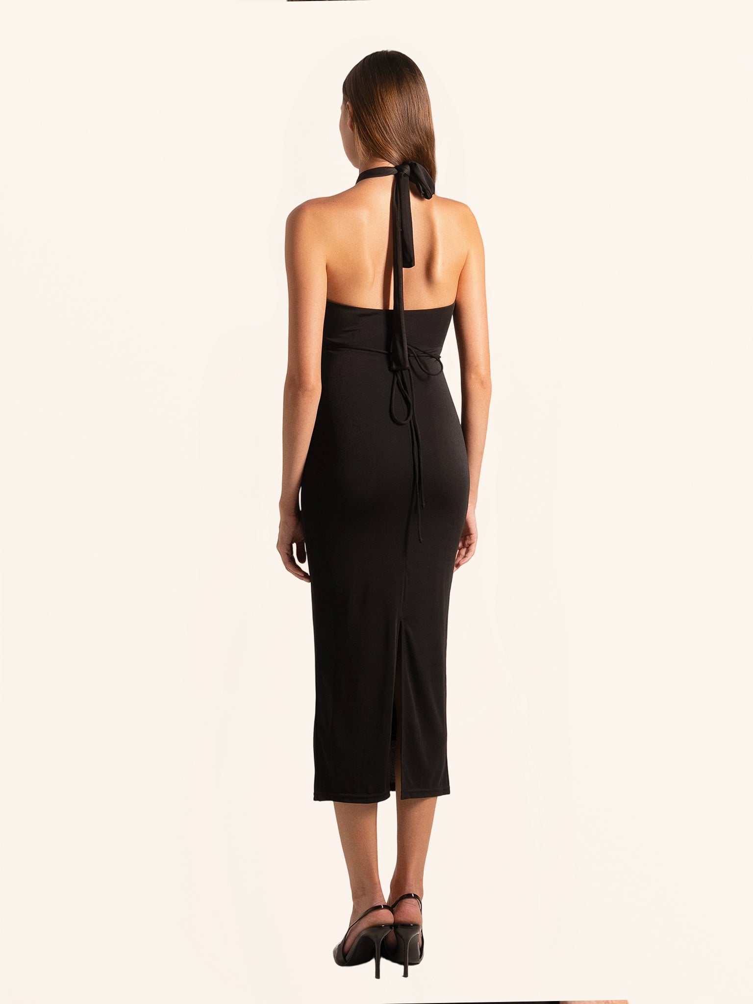 Back view of black cut out midi dress with halter strap and open back