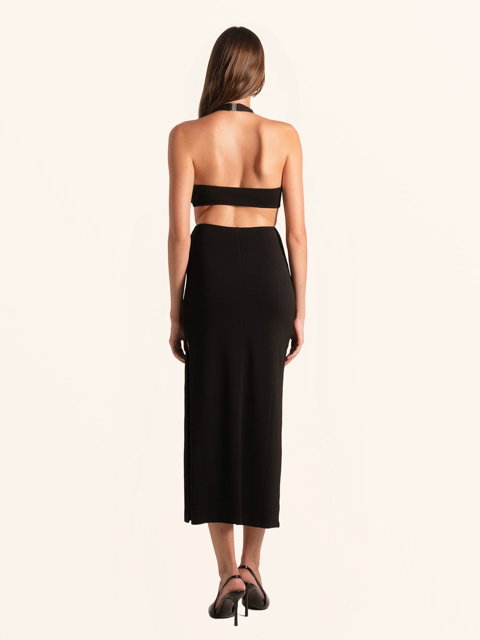 Rear full view of black deep V cut out dress with halter neckline