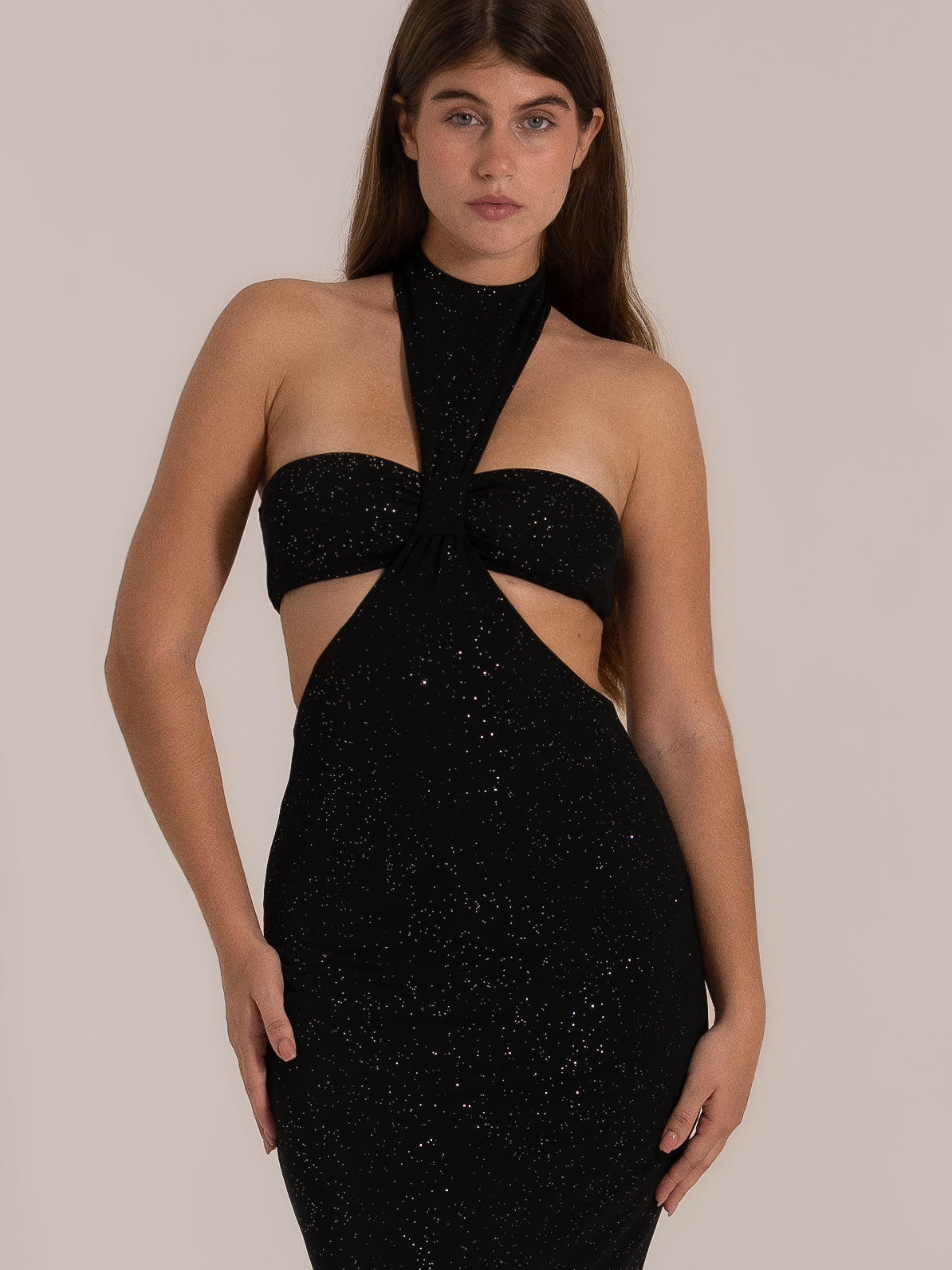 Front view of black halter neck cutout dress with glitter detail and fitted silhouette