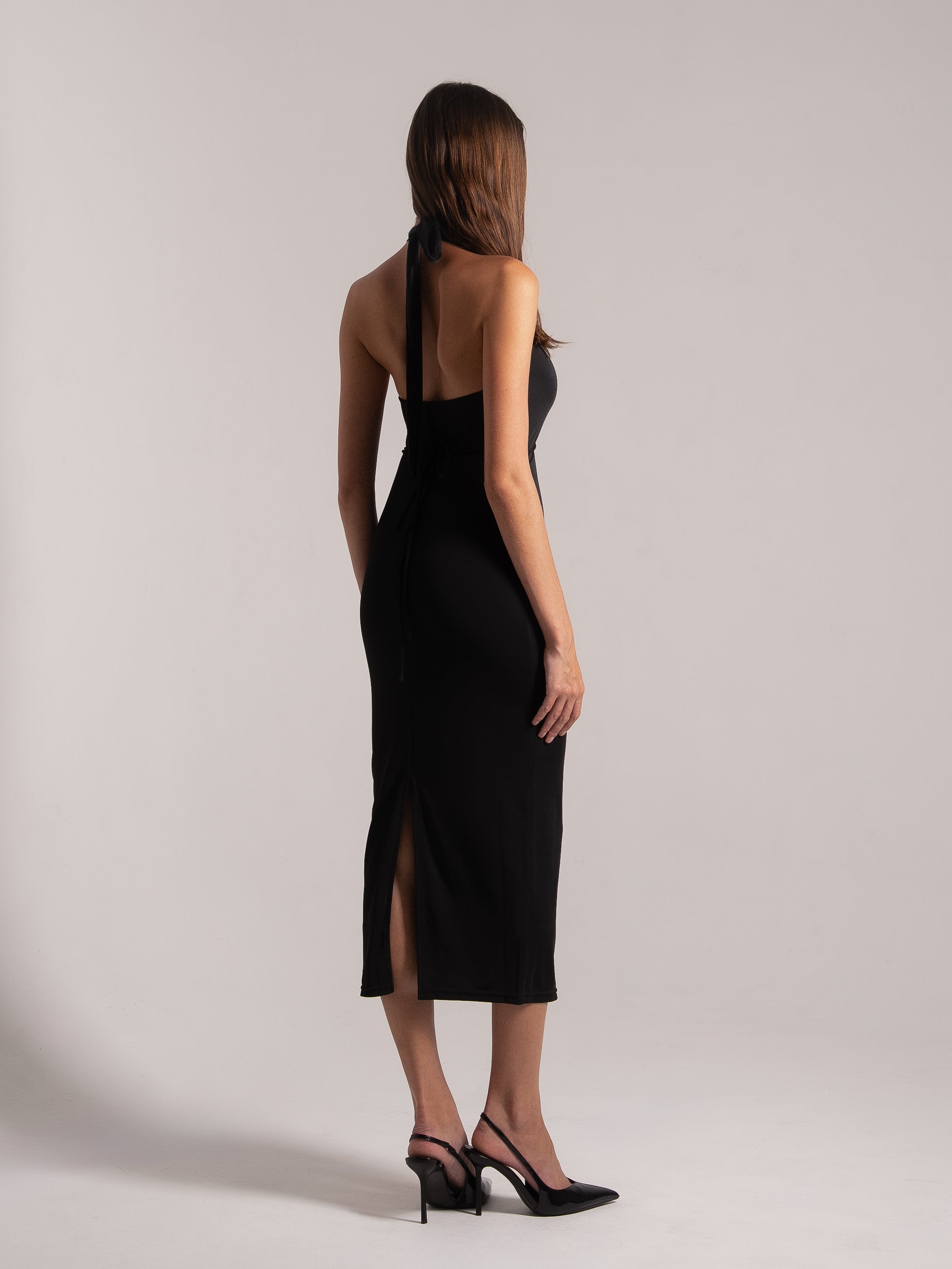 Side‑back view of black halter cutout midi dress with side slit