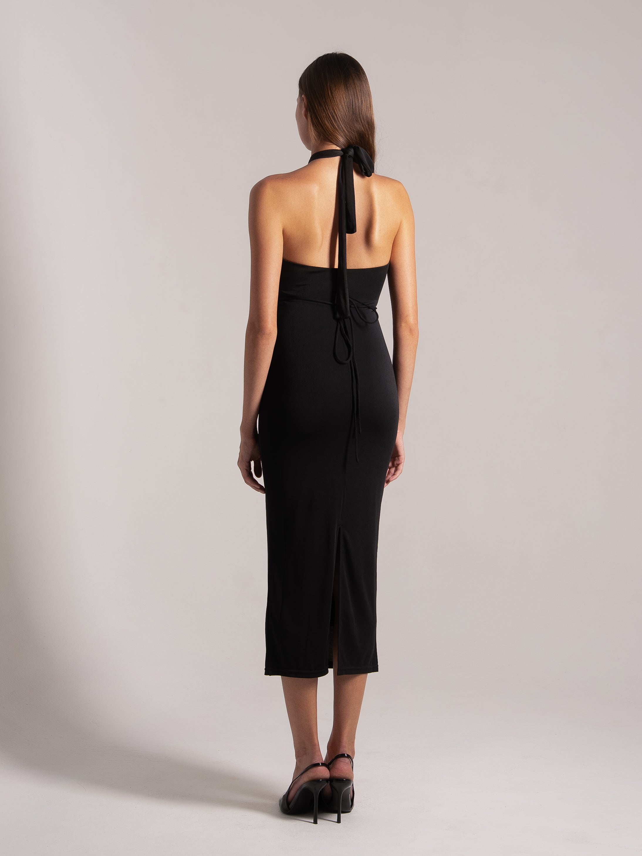 Back view of black halter tie‑back cutout midi dress