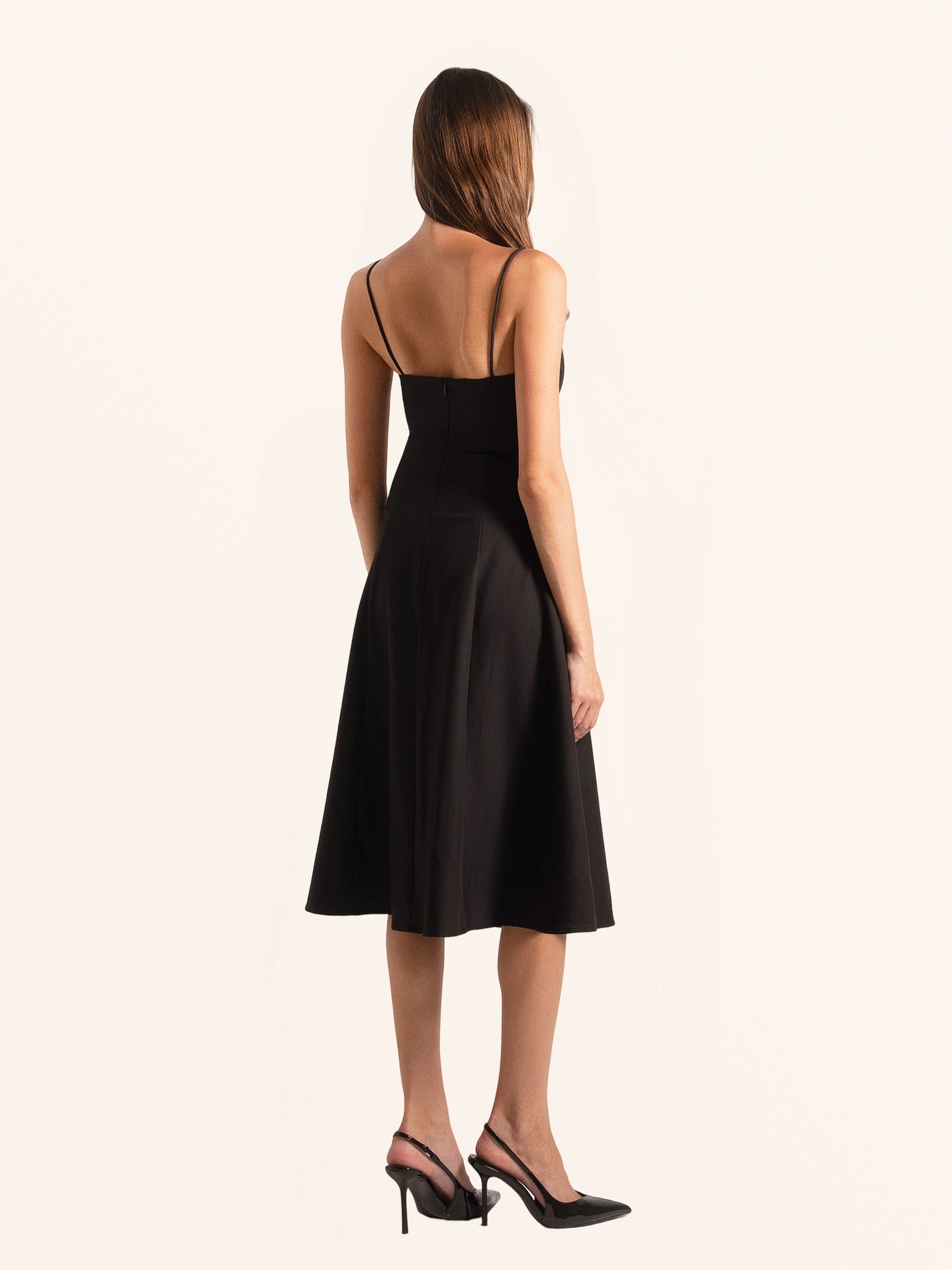 Rear side profile of black midi dress showing flared skirt design