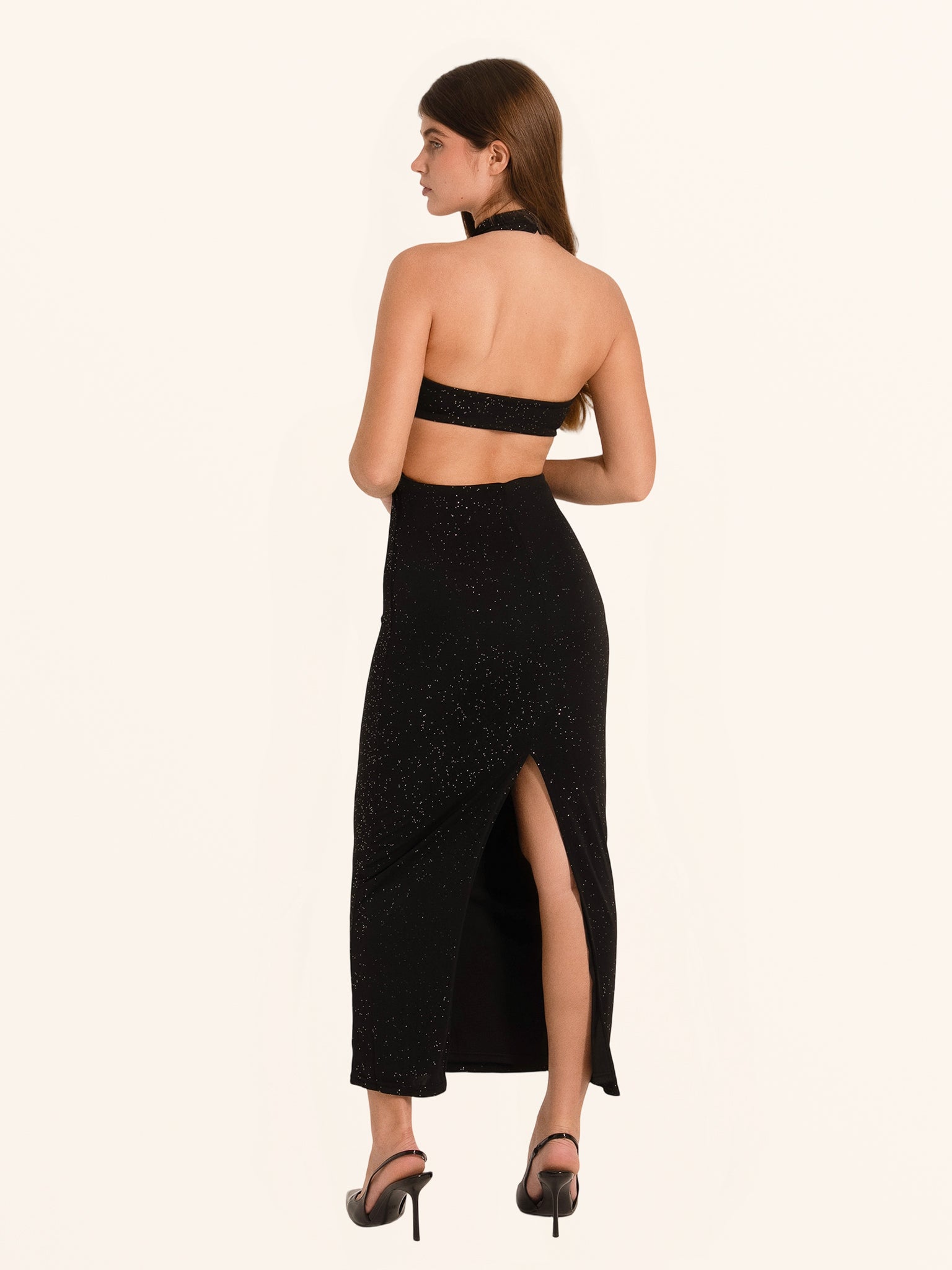 Rear side angle of black sequined cut out dress with back slit hem