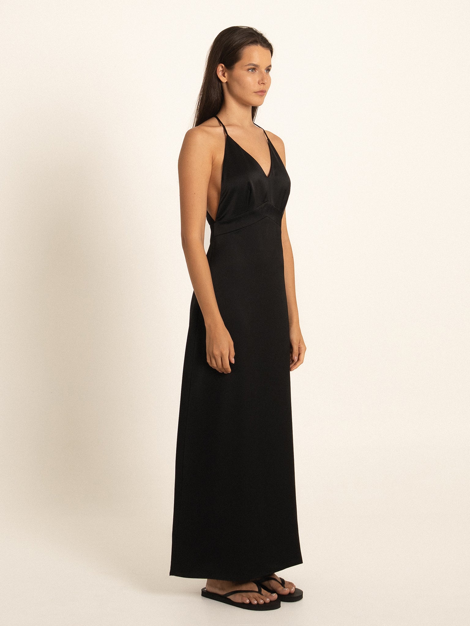 Side angle of black spaghetti strap maxi dress with flowy hemline