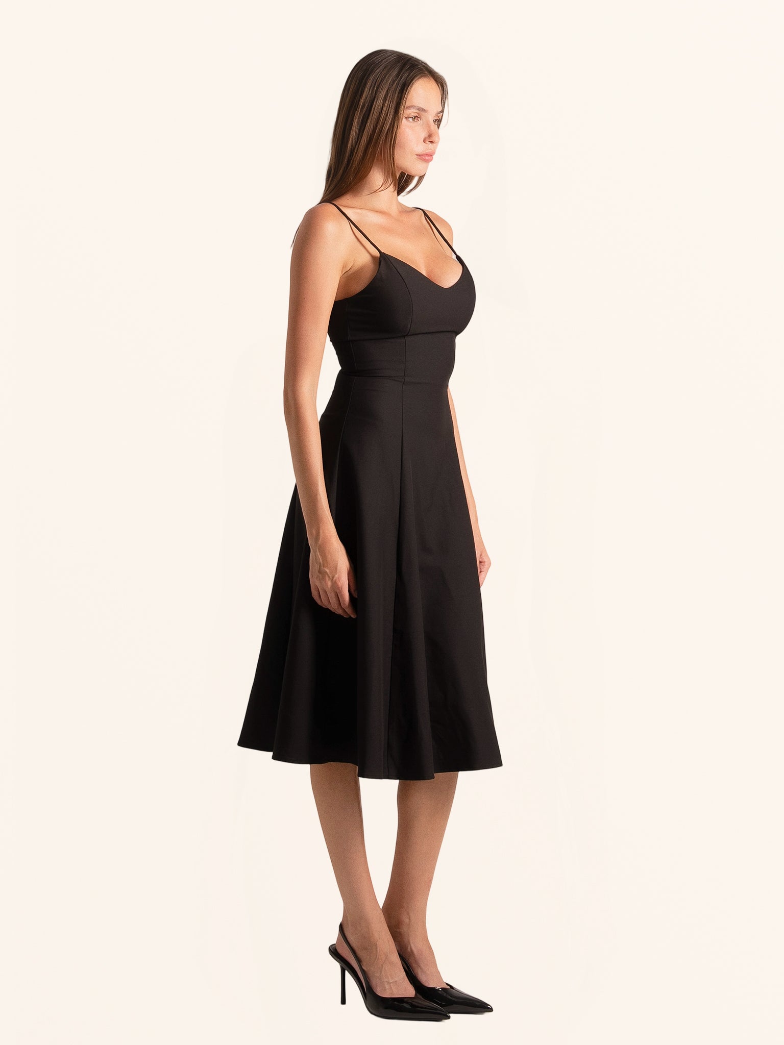 Full body look of black spaghetti strap midi dress with A-line cut