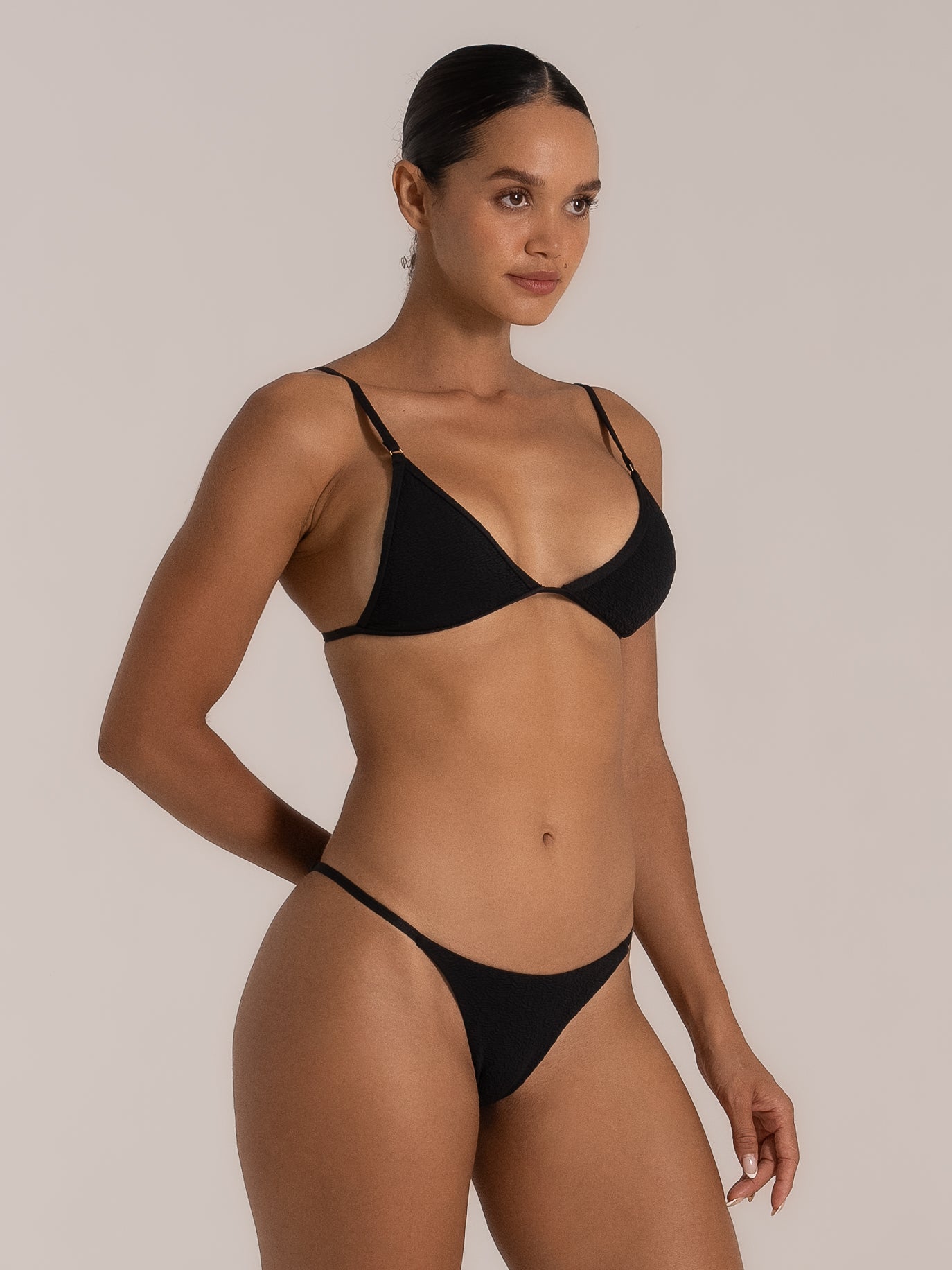  Side angle of black string triangle bikini top featuring subtle texture