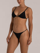 Side view of woman in a black textured bikini with adjustable straps and minimal coverage
