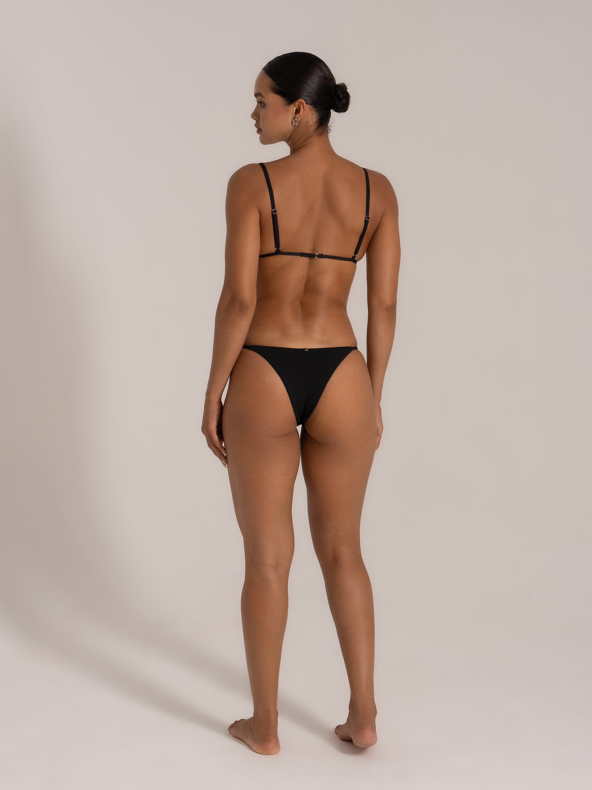 Back view of model showcasing the adjustable strap design of a black triangle bikini set