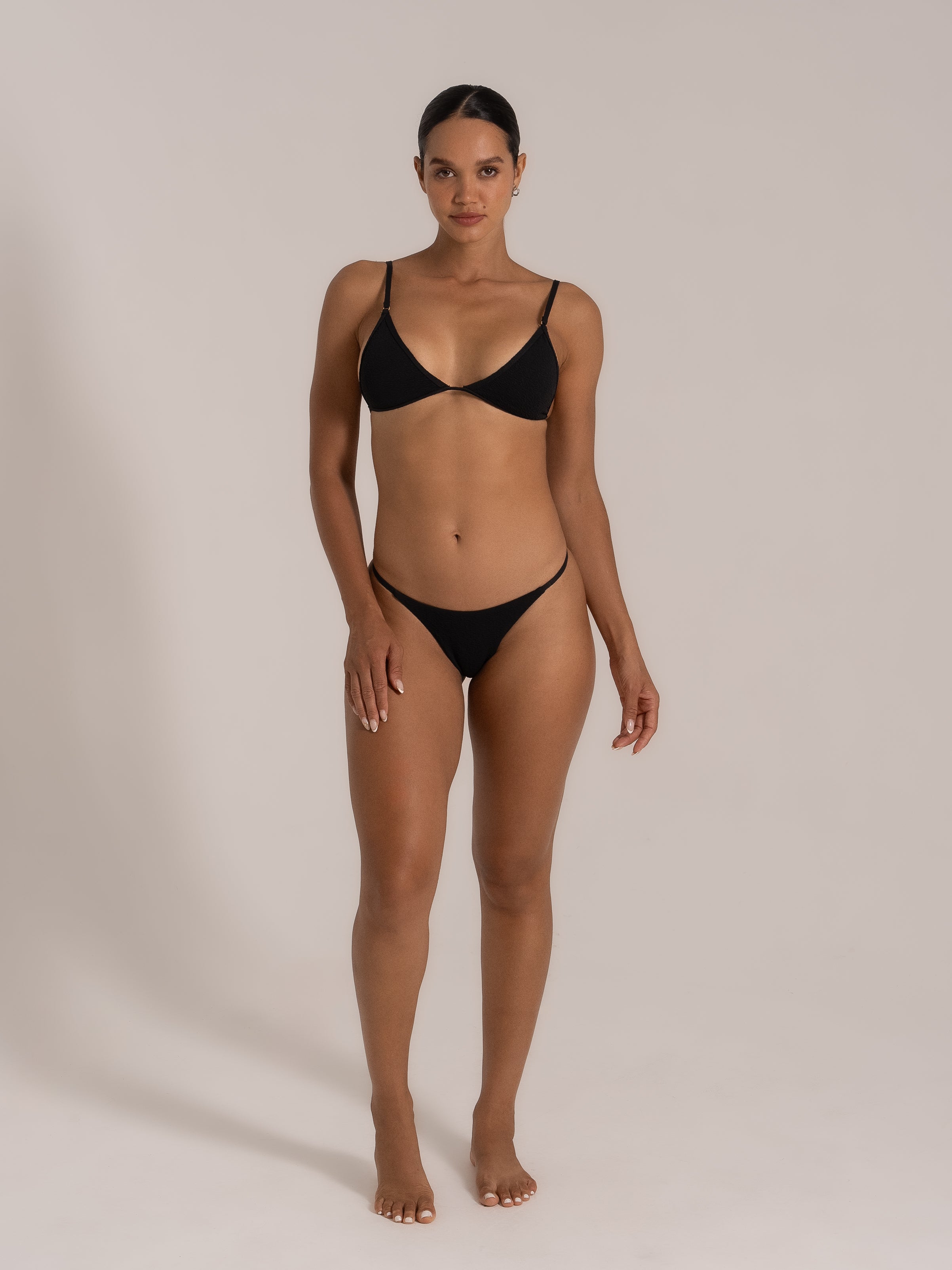 Front view of model wearing a black triangle bikini set with adjustable straps