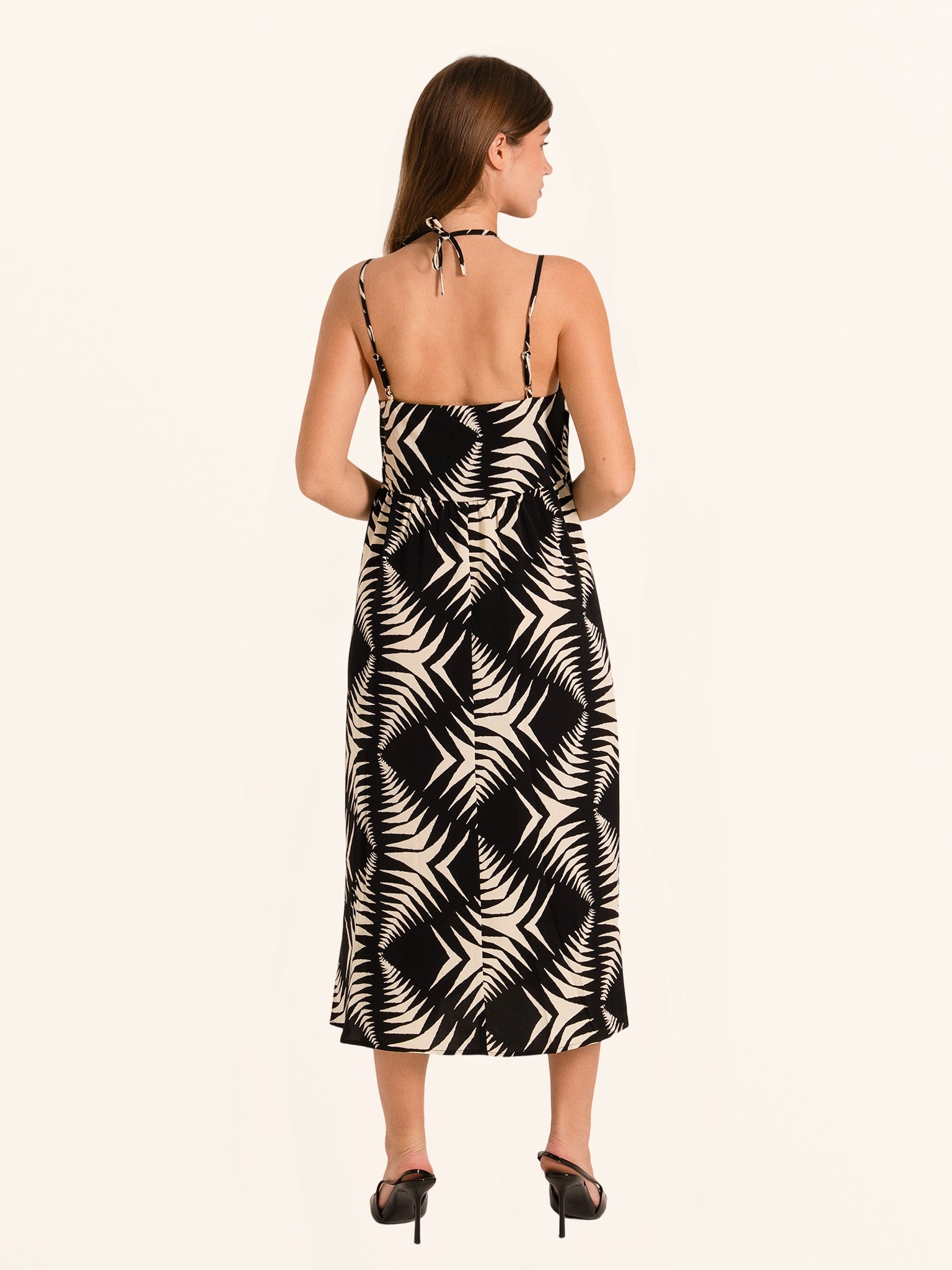 Rear side angle of black and white leaf print midi dress with flowy hemline